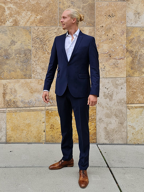Lars Thieme, Webdesigner von Maze-Design steht in einem dunkelblauen Anzug vor einer Wand