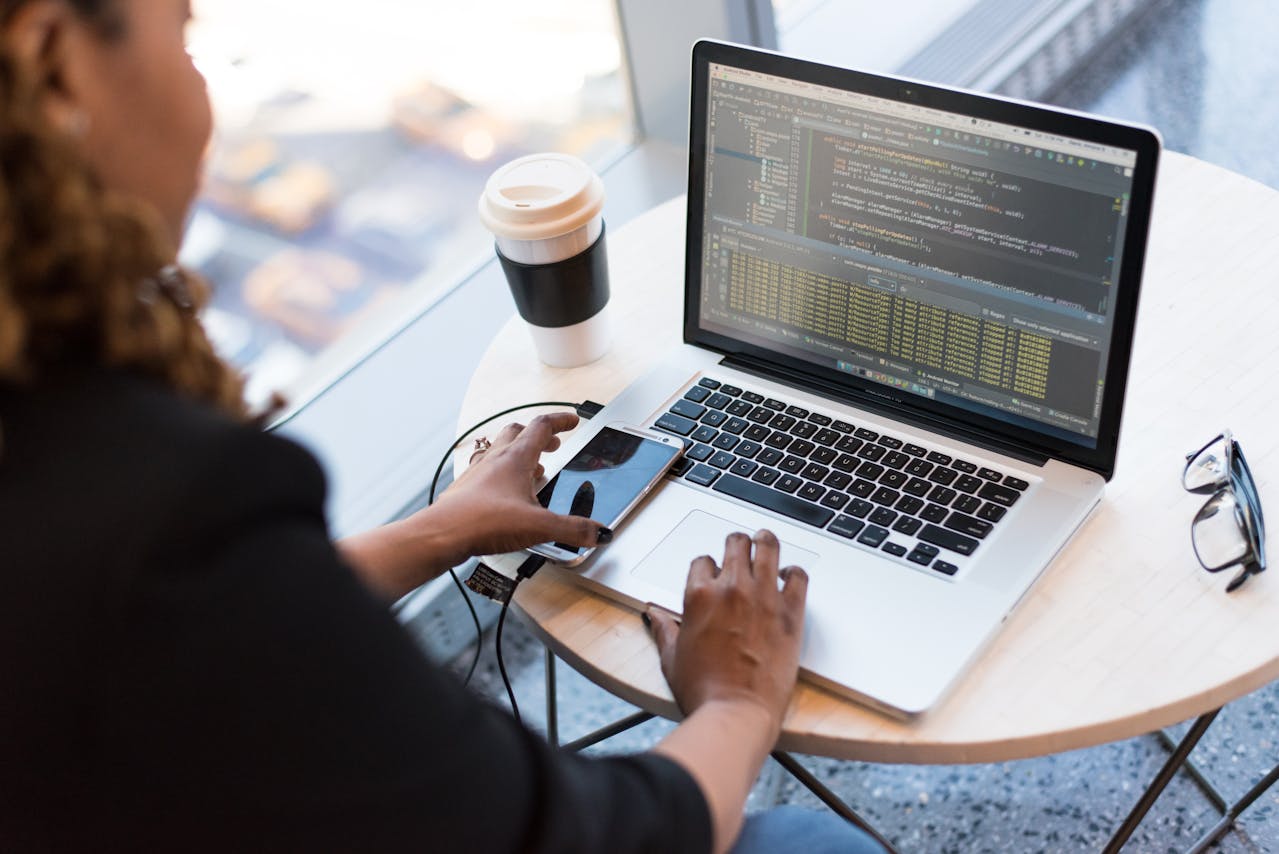 Programmiererin arbeitet am Laptop mit Kaffee.